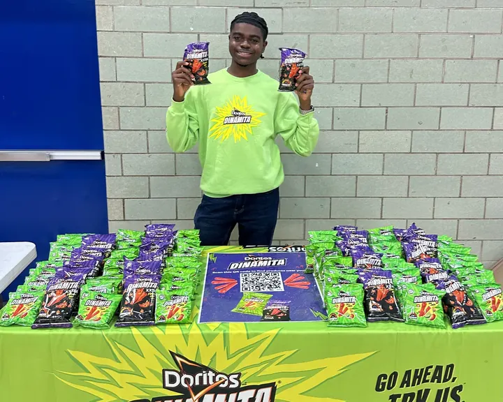 An Evolve Brands student Brand Ambassador running a snack sampling table on a college campus